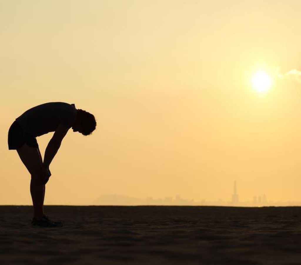 Silhouette of an exhausted sportsman at sunset with the horizon in the background
